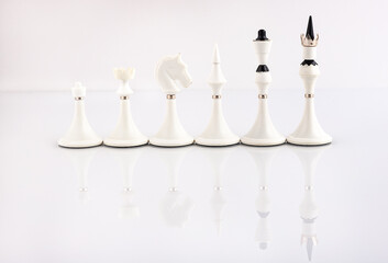 White chess pieces on a reflective surface. Business concept. Game, strategy, wisdom, determination.