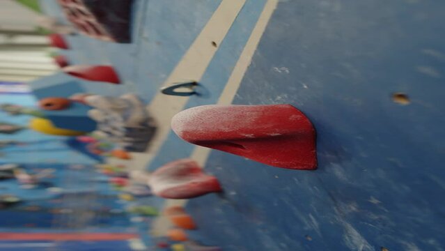 Vertical close up shot of red hold on climbing wall in indoor gym