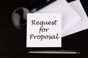 Conceptual hand writing Request for Proposal message on a white sticker with pen on a black table.