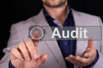 Businessman on a black background pressing an Audit concept button.