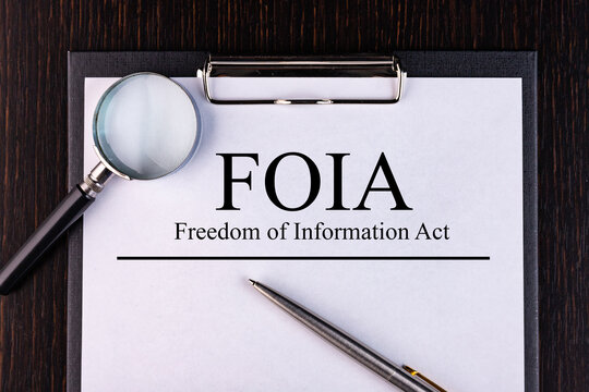 Text FOIA Act. is written on a notebook with a pen and a magnifying glass lying on the table. Business concept.
