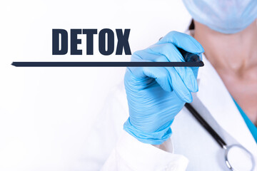 DETOX text is written with a marker held by a doctor with a stethoscope. Medical concept.