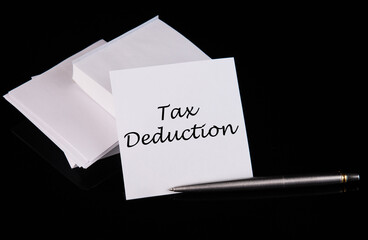 Conceptual hand writing Tax Deduction message on a white sticker with pen on a black table.
