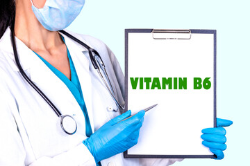VITAMIN B6 text is written on a tablet which the doctor holds in a medical gown and gloves. Medical...