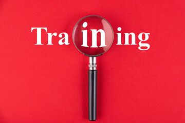 TRAINING text written through a magnifying glass on a red background. Business education concept.