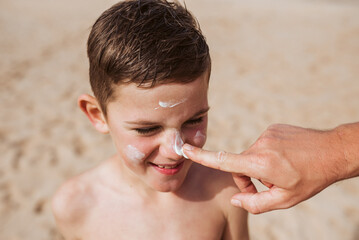 Boy with sunscreen lotion on face. Young boy si protected from sun with sunscreen. Concept of beach summer vacation with kids.