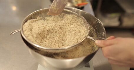 Sifting ground nuts through a sieve. Professional baking, cake making, confectionery.