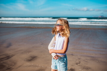 Girl with broken arm on beach. Young blonde girl has arm cast, injured during family vacation in...