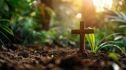 Small wooden Christian cross in the ground and lush nature forest in background and copy space