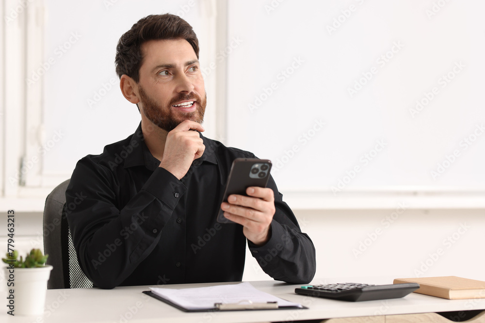 Poster smiling man with smartphone at table in office. space for text