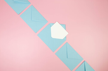 Top view of light blue envelopes, white card on pink background. Post flat lay. Copy space.
