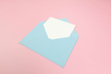 Top view of light blue envelope, white card on pink background. Post flat lay. Copy space.