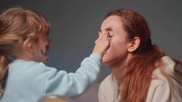 Little girl applying makeup to her mother. time spent with the child