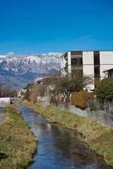 Quiet river flowing through a residential neighborhood of Vaduz, Liechtenstein on a bright winter day