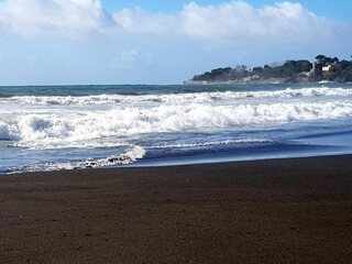 Tropical beach with waves breaking on the black sand and turquoise water