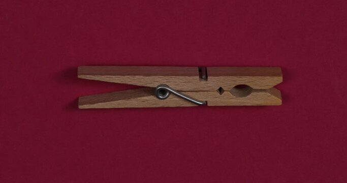 Wooden clothespin on red color background. Loopable stop motion animation. 4K top view closeup. 