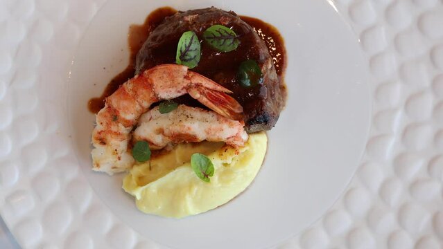 Surf and turf dish. 4K video with a surf and turf gourmet plate made from shrimps, beef tenderloin filet mignon steak and mashed potatoes.