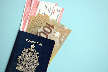 Obraz premium Canadian passport with money and airline tickets on blue background close up. Tourism and travel concept