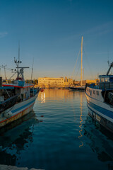 Vista panoramica sul porto di Trani al tramonto con barche e pescherecci di pescatori. Puglia,...