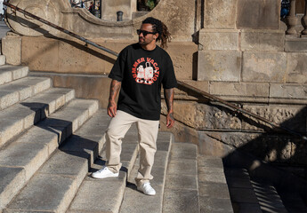 Mockup of man in customizable t-shirt on steps - obrazy, fototapety, plakaty