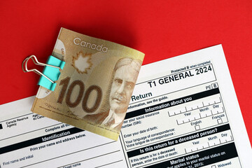 Canadian T1 General tax form Income tax and benefit return lies on table with canadian money bills close up. Taxation and annual accountant paperwork in Canada - obrazy, fototapety, plakaty