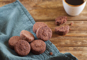Chocolate cookies lie on a towel on a wooden table