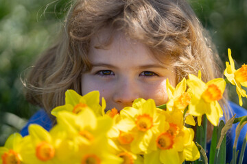Spring fun for kids. Child play outdoors in a beautiful spring garden. Kid face in flowers. Adorable little kid in blooming cherry garden on beautiful spring day. Happy child during spring blossom.