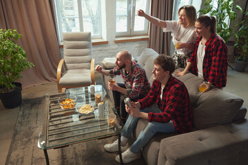 Emotional young people, friends gathering in living room at home, eating snacks, drinking beer and watching online football match translation. Concept of sport, championship, leisure and entertainment - obrazy, fototapety, plakaty
