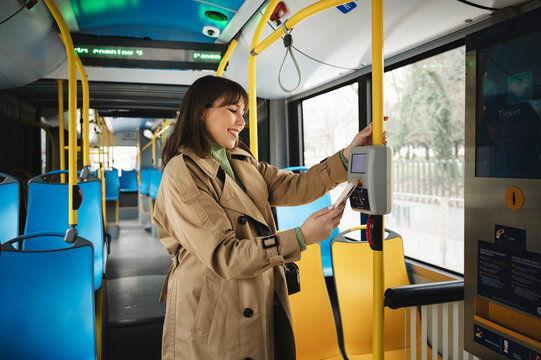 Happy passenger buying ticket in bus through contactless payment using smart phone