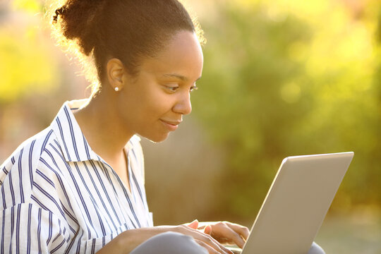 Black woman in a garden using laptop