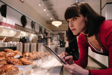 Baker taking inventory near baked pastry items in store