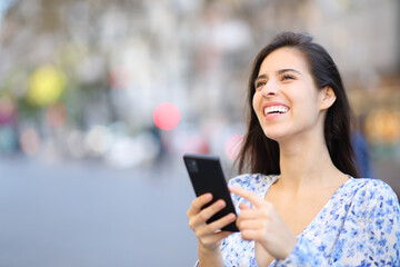 Happy woman laughing looking above holding phone
