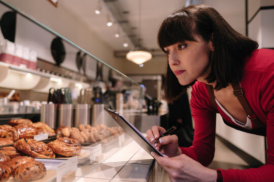Baker taking inventory near baked pastry items in store