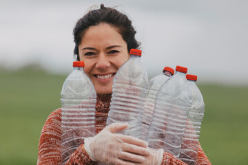 Happy volunteer holding plastic bottles at countryside