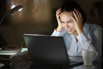 Desperate businesswoman checking laptop in the night