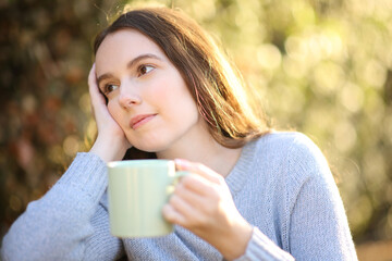 Woman dreaming drinking coffee in a garden