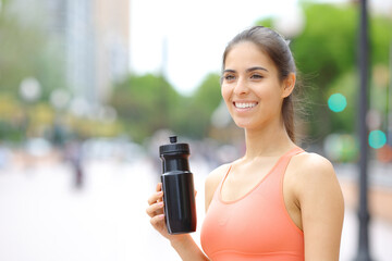 Happy runner holding water bottle after sport