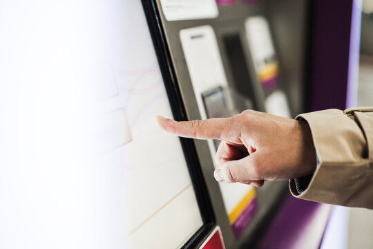 Woman touching screen of ticket vending machine at train station