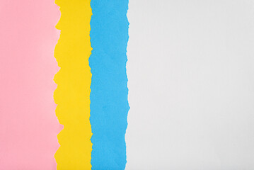 Blue, yellow and pink colored papers torn on a white background.