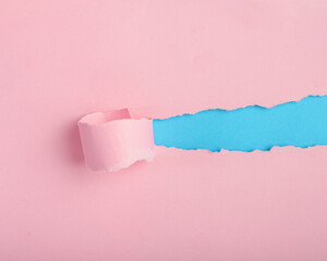 Torn pink paper revealing blue background. Background, paper texture.
