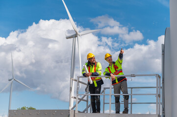 Two workers on a platform looking at a wind turbine