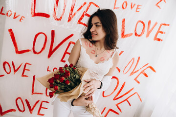 Woman sitting on chair with kisses lipstick is holding a bouquet of red roses, drawings of the word...