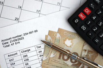 Fototapeta premium Many calculation results in schedules lies on table with canadian money bills, calculator and pen close up. Taxation and annual accountant paperwork in Canada