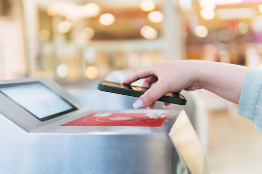 Hand of woman scanning QR code through smart phone at turnstile