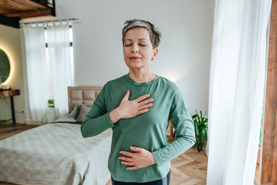 Woman practicing breathing exercise with eyes closed at home