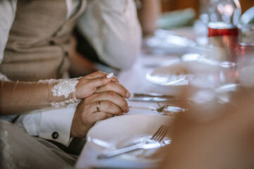 Valmiera, Latvia - Augist 13, 2023 - .Close-up of clasped hands at a dining table, with a focus on...