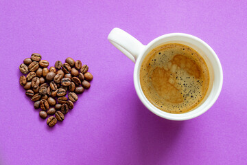 white cup of black espresso coffee on purple violet background, with a place for inscription,  with heart shaped coffee beans 