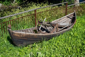 An old abandoned rowing boat  with fishing reel on grass