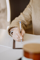 close-up of a woman's hand writing with a pen on paper