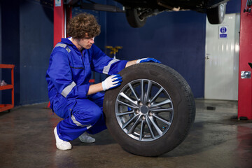 mechanic holding and checking a tire for fixing in garage